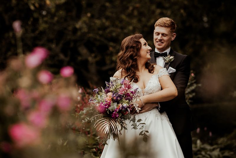 Couple holding a bouquet together in the garden on their wedding day